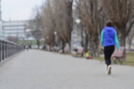 海滨附近春天公园的景观模糊。 前面的道路装饰着树木和堤坝的低矮栅栏