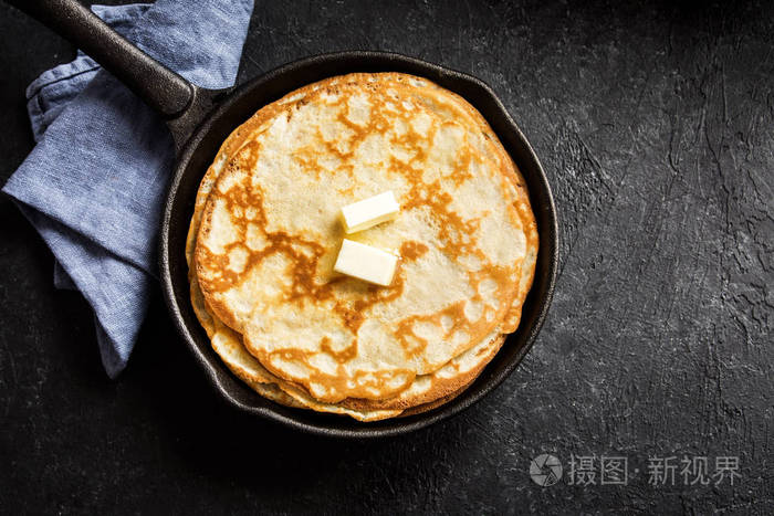 自制的奶油薄饼,在铸铁锅中,在乡村黑色背景上,复制空间,烹饪新鲜的