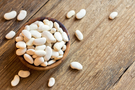 有机生白豆在木碗中，为饮食素食素食蛋白质食物烹饪准备好的菜肴提供健康的配料