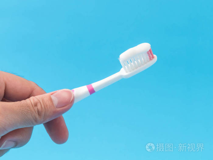 特写的男人手拿着牙刷蓝色背景