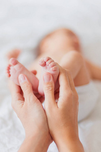 母亲抱着刚出生的婴儿的双脚。在女人的手的小脚。舒适的上午在家