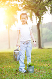 亚洲小女孩浇水植物在户外