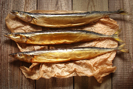 木制背景上熏制的鱼秋刀鱼图片