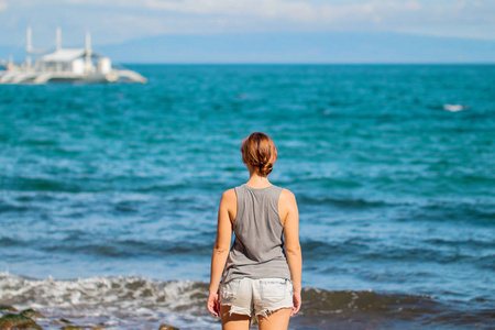 衬衫和短裤在海滩上的女人。明亮的年轻女孩看巡航船照片