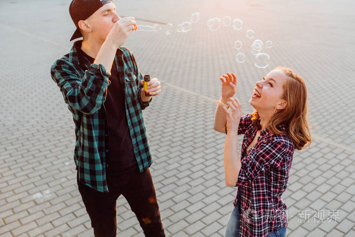 年轻漂亮的女人和年轻时髦小男孩吹 bubblesand 痴情