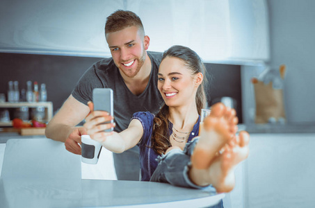 使用智能手机坐在厨房对幸福的夫妇