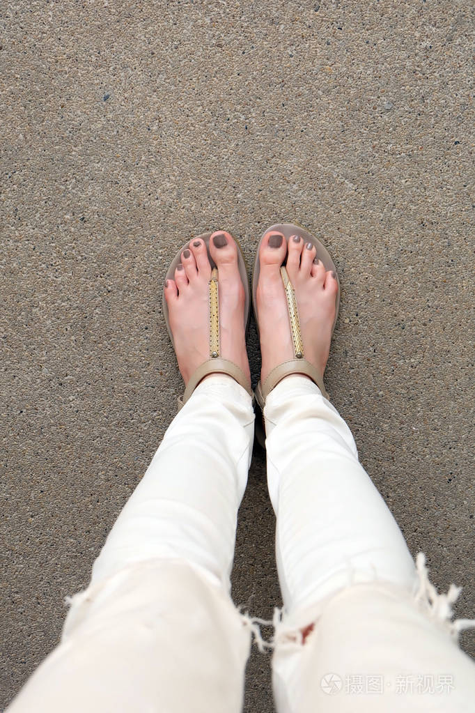 在地面上穿凉鞋和白色牛仔裤的自拍脚