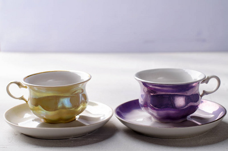 空的五彩瓷器餐具。黄色和紫色杯淡紫色背景