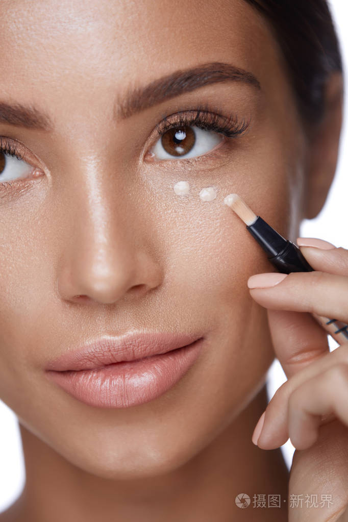 化妆品美丽的女人应用遮瑕膏做化妆