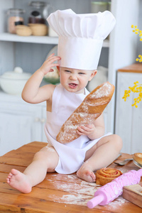 宝宝烹饪的自制蛋糕。早春，复活节和一个小女孩在厨房里的厨师服装烤面包和饼干。那女孩弄脏与面粉了。妈妈的帮手