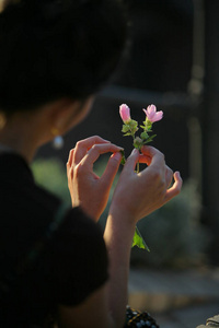 的三岁女孩,穿着白色的紫罗兰色裙子,开心地笑着,手里拿着一朵小花,和