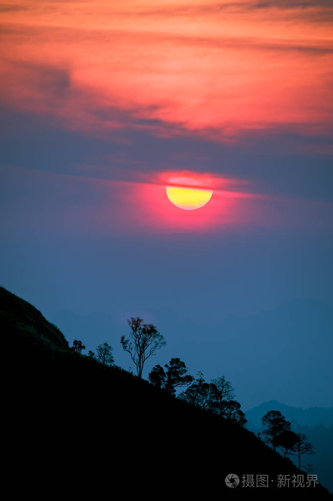 夕阳在山,与风景秀丽的日落太阳在色彩斑斓的天空背景树剪影照片