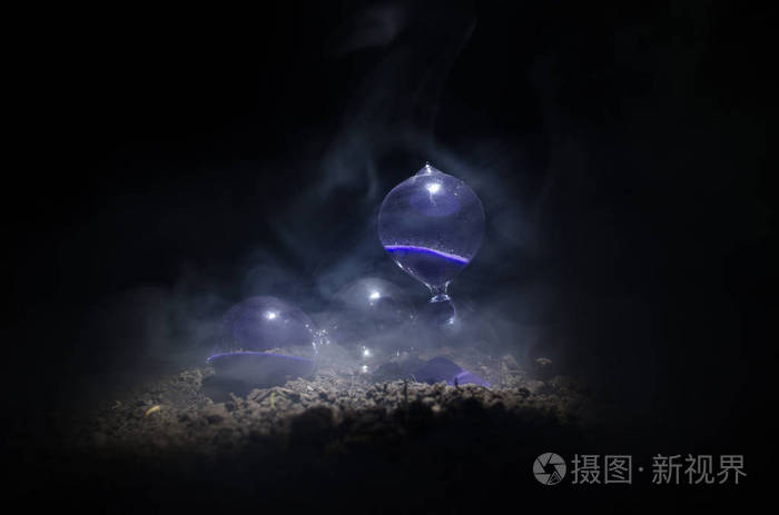 沙漏时钟和烟在黑暗的背景,与热黄色橘红色的光或符号与副本空间