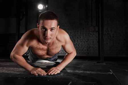 在做俯卧撑对砖墙在运动量来找到健身房运动服的年轻肌肉男