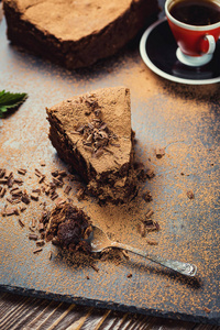 巧克力蛋糕，糖果和一杯咖啡，巧克力蛋糕切的一块与叶片上灰色的背景，特写，黑巧克力蛋糕 素食巧克力蛋糕，美味的巧克力蛋糕上木制背