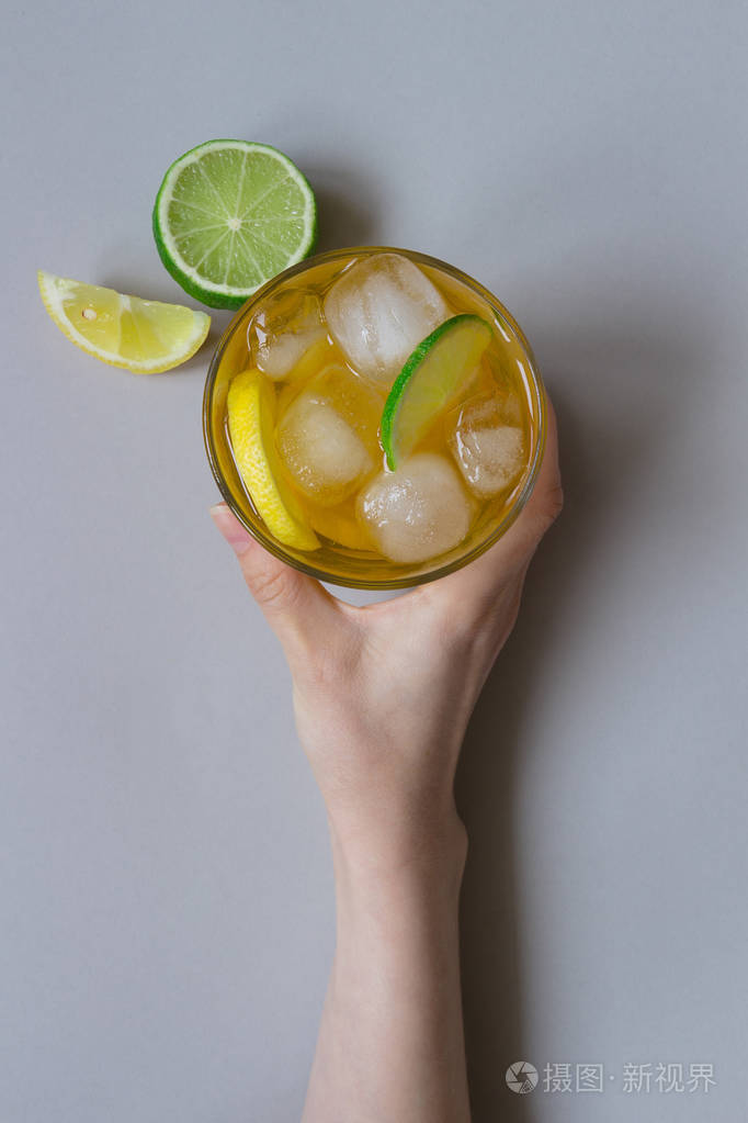 手拿着冰喝柠檬和酸橙光的蓝色背景顶视图