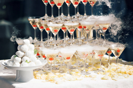 关于事件 聚会或宴会的香槟金字塔。玻璃杯里的樱桃。乾冰浮在水面上