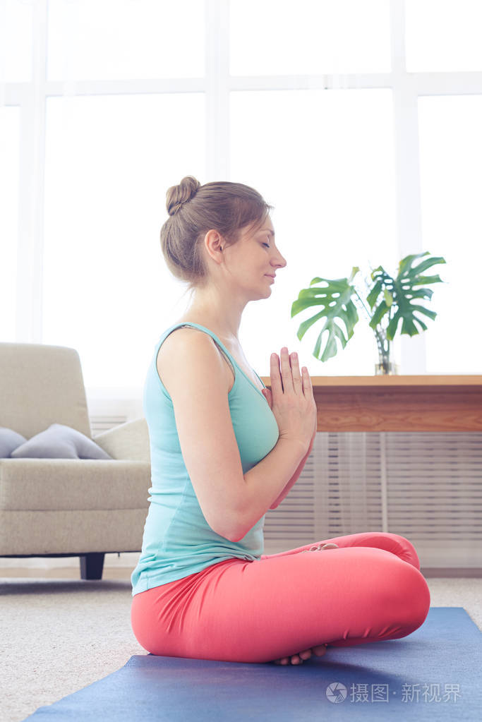 平静美丽的姑娘坐在瑜伽垫上瑜伽冥想