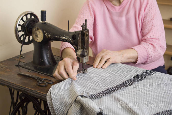 一位白发老太太上旧缝纫机缝制.剪裁的一位女裁缝师老妇