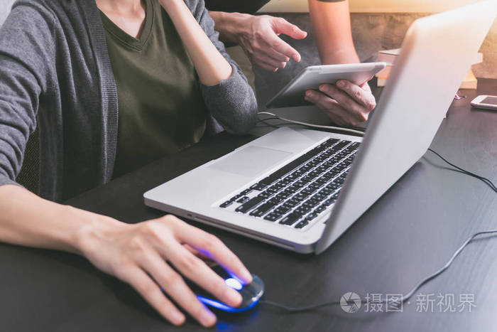 商业伙伴办公室伏案工作在一起,他们正在使用一台笔记本电脑和平板