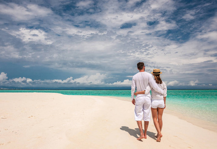 夫妇在白色行走在马尔代夫的海滩上
