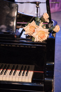 大橙色玫瑰躺在一架黑色的老钢琴上, 钢琴上有钥匙