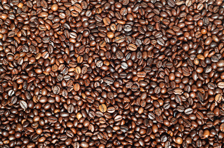 背景质地有大量芳香新鲜的棕色烤咖啡粒。 制作天然咖啡的阶段之一