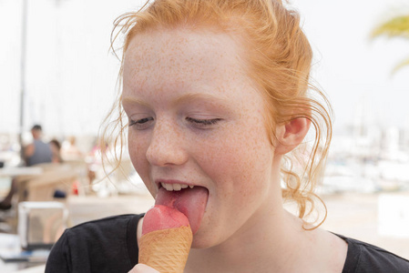 年轻女子在锥户外吃粉红色冰淇淋