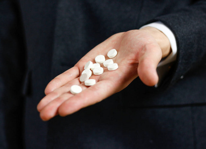 商人手里拿着大量的白色药片和平板电脑包照片