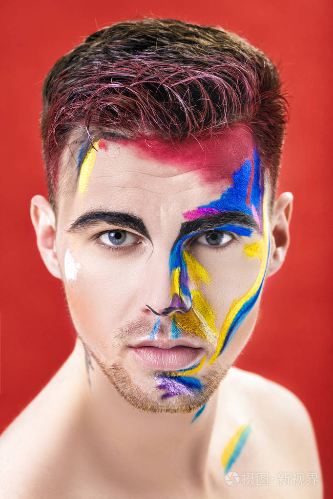 年轻有魅力的男人,与色的面漆红色背景上的肖像.专业化妆时尚.