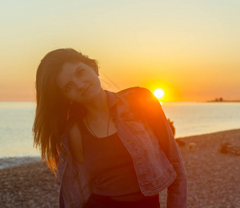 年轻漂亮的女性，在日落的时候在海滩上