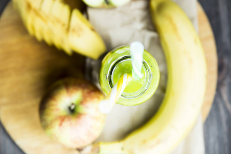 菠菜和黄色的苹果从原始的苹果和香蕉,黄色和绿色的管透明瓶新鲜果汁