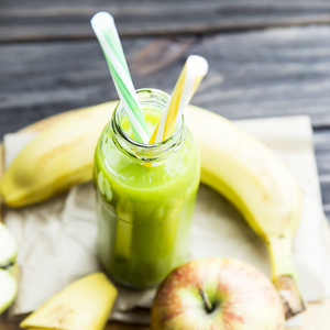 从原始的苹果和香蕉，黄色和绿色的管透明瓶新鲜果汁
