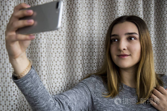 黑头发的年轻女孩对她的智能手机并拍照