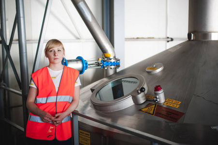 在啤酒厂的女工。肖像女子穿着长袍，站在背景线食品生产 生产检验管理控制设备