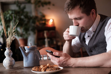 一个年轻人在一个白色的衬衫和背心早餐一杯茶