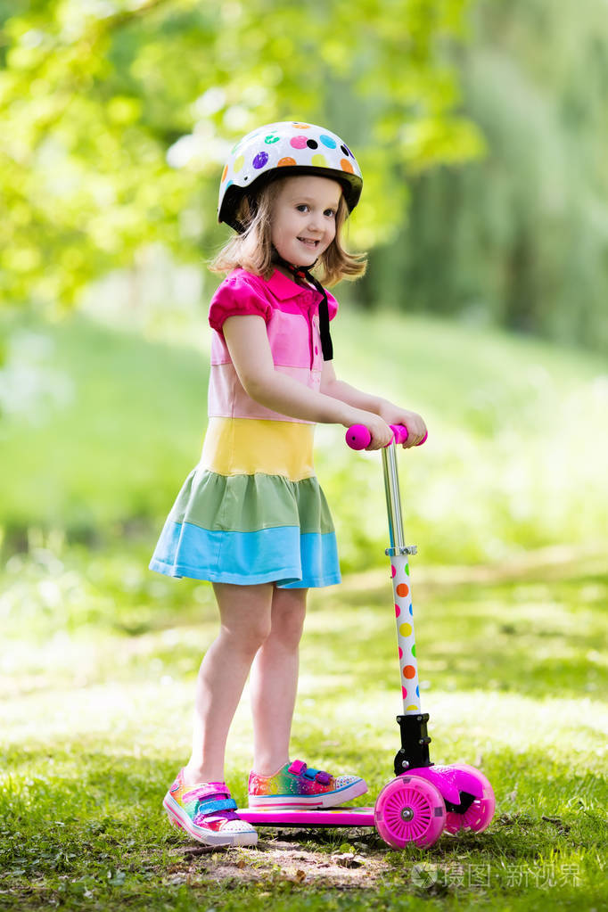 小女孩骑着多彩的滑板车