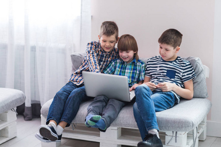 孩子们在家里坐在沙发上，玩笔记本电脑