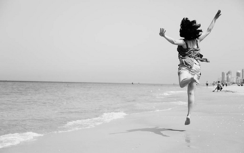 成熟的女人在海滩上跳跃