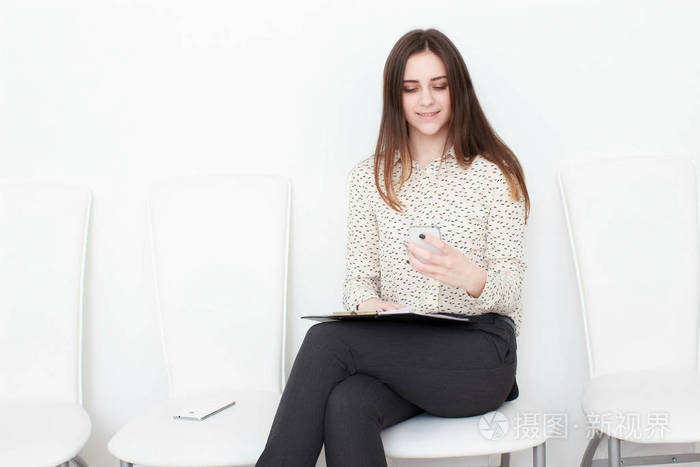 行政商务女人使用智能手机，坐在椅子上，一个白色的背景上孤立