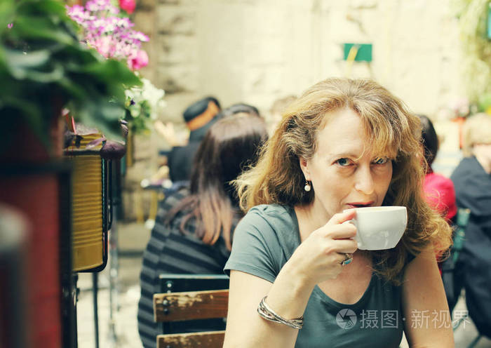 成熟的女人坐在户外咖啡馆