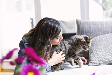 女人和她的猫在客厅里玩照片