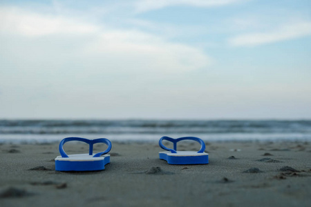 旅游概念，与海洋背景下海滩上的鞋子