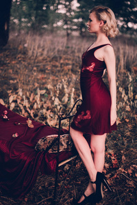 美丽和优雅的金发女子，红红的嘴唇和头发波摆在床上在户外秋天，复古的复古风格和时尚的穿着酒红色睡衣