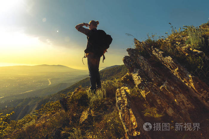 旅游与背包站在山顶上享有山谷的景色在晴朗的一天