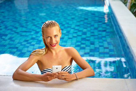 在游泳池中使用智能手机的女人