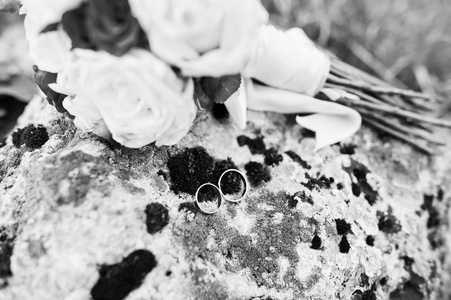 婚礼花束与圆环在长满了苔藓的石头