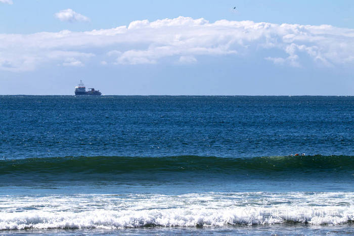海洋和波浪和集装箱船在多云的天际线