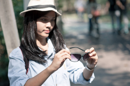 美丽的年轻亚洲女子头戴圆形帽子上一个公园，在夏日旅行