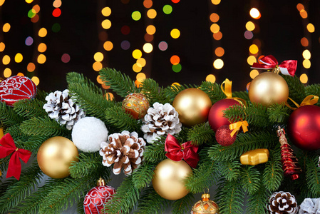 圣诞装饰上白色的皮毛与杉木树分支特写 礼品 圣诞球 锥和其他对象在黑暗的背景 灯光和照明 冬天假日概念